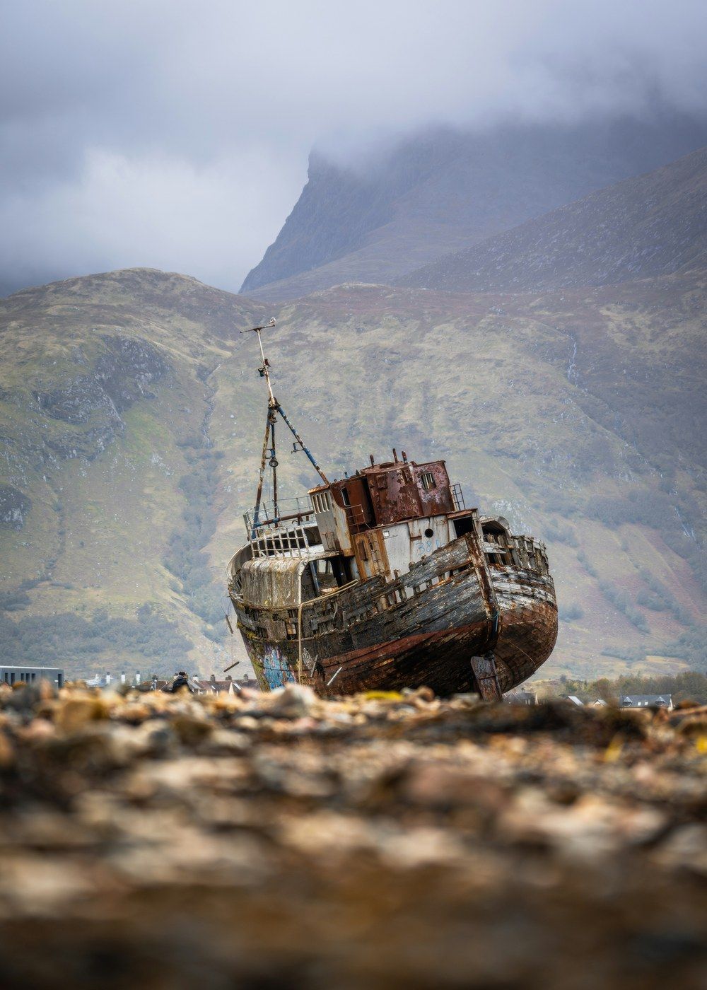 A weathered shipwreck beached beneath a mist-wrapped mountain.